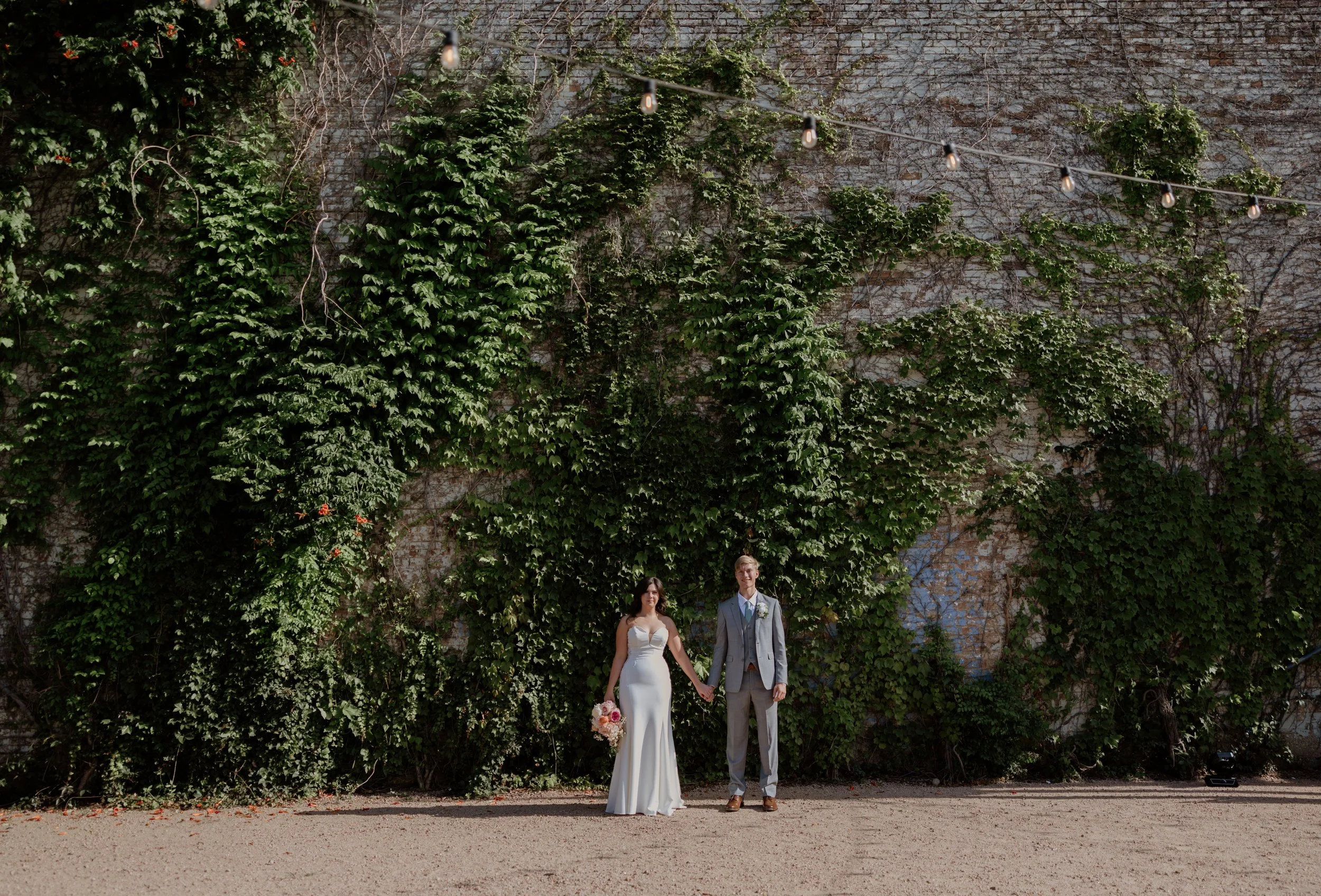 Fort Worth Wedding at The Brik, couple holds hands in front of the ivy-wall.